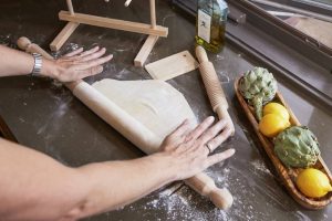 Beech wood pasta rolling pin on a wooden table with fresh pasta dough.