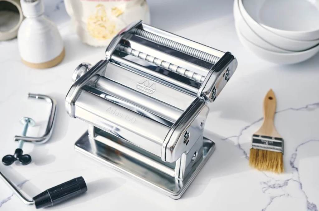 Close-up of Marcato Atlas 150 pasta maker rollers being brushed clean with a dry tool for safe maintenance