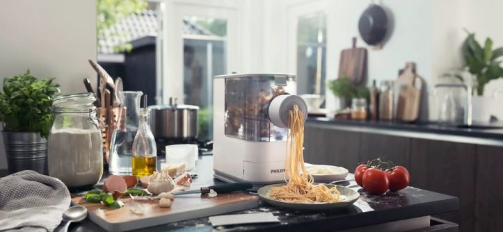 Philips pasta maker extruding fresh noodles in a modern kitchen.