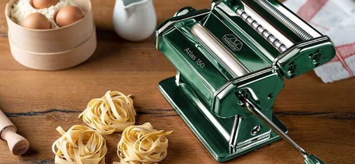Chef using a professional pasta machine to roll fresh pasta dough.