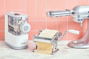Home cook using an electric pasta machine to make fresh noodles.