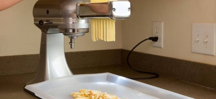Home cook carefully cleaning a pasta machine to avoid damage.