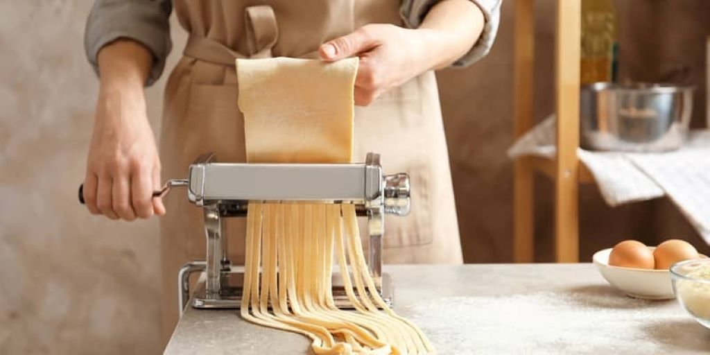 Close-up of pasta maker being wiped and maintained properly.