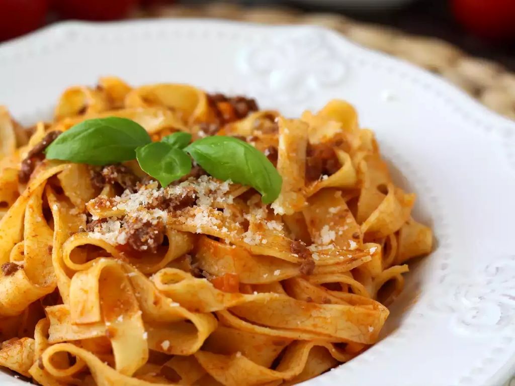 Classic Italian pasta dishes including lasagna and tagliatelle al ragù on a rustic table.