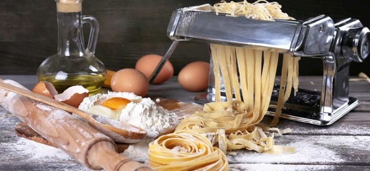 Close-up comparison of manual crank and electric pasta maker with repair tools.