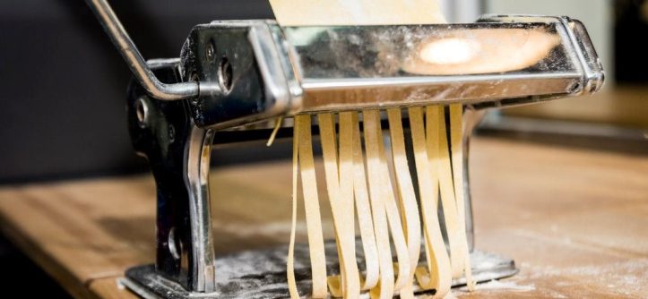 Close-up of a jammed pasta maker being repaired in a home kitchen.