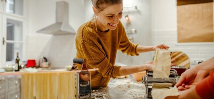 Home cook using a guide to troubleshoot a pasta maker with dough stuck inside.