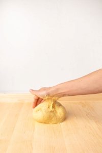 Close-up of pasta dough tearing while being rolled through a pasta machine.