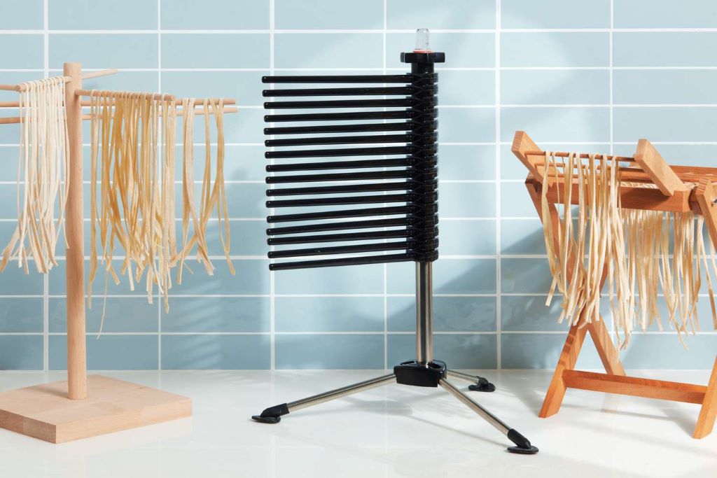 Foldable pasta drying rack holding strands of pasta for homemade cooking preparation.