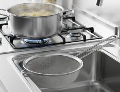 Safely draining boiling water using a mesh pasta strainer in a home kitchen
